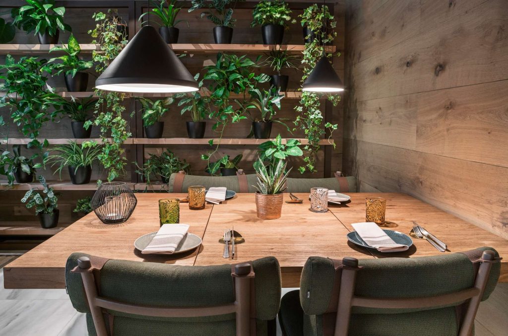 Una zona de un restaurante con una mesa de madera y plantas.